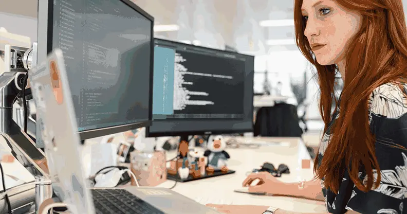 Professional exploring ai course details while coding on a laptop with dual monitors