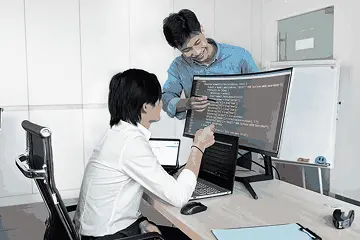 Career switcher exploring an artificial intelligence course for beginners with a mentor at a desk